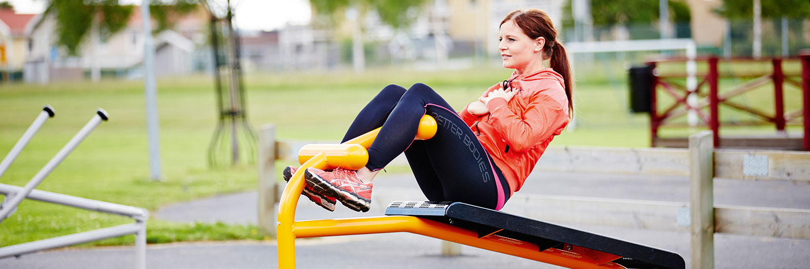 A woman is exercising on a workout bench, she is doing crunches. 